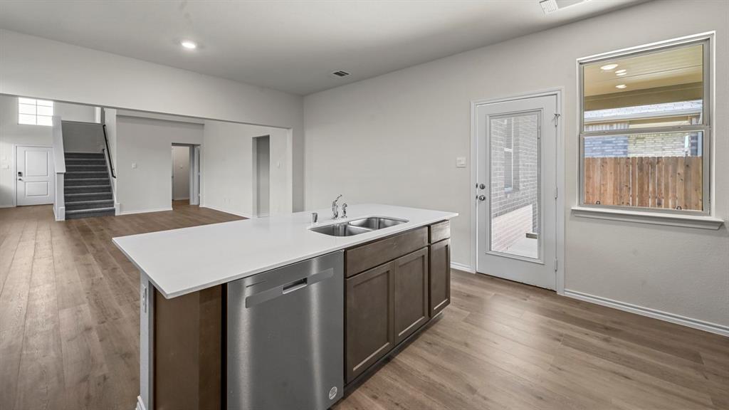 Kitchen island featuring an undermount double sink, stainless steel dishwasher, and a light-toned countertop