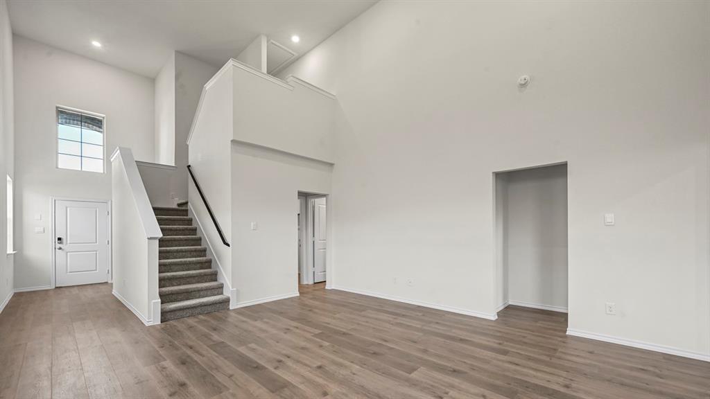 High ceilings, wood-finish flooring, two-story entry, carpeted staircase, and an upper-level landing