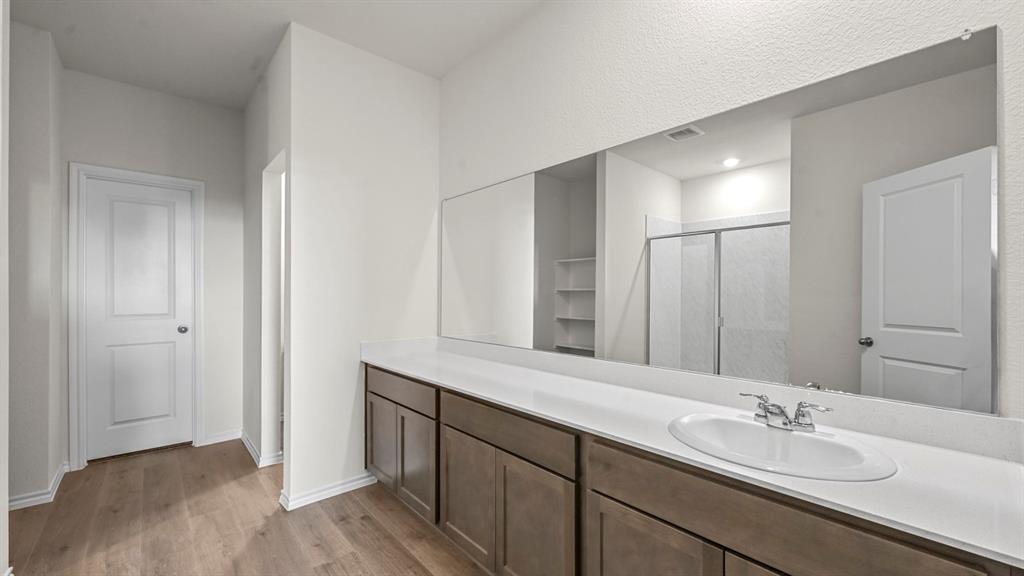 Spa-inspired primary bathroom featuring an extended vanity with wood-finish cabinetry, white quartz countertop, and chrome fixtures