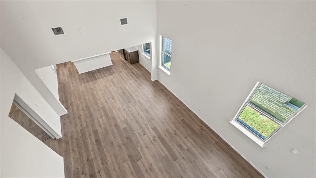 Vaulted ceiling with skylight, wood-finish flooring, white walls, and recessed lighting