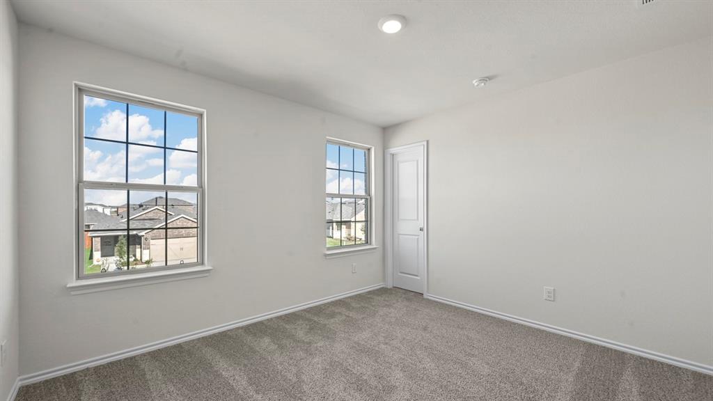 Recessed ceiling lighting, carpeted flooring, two windows with grids, and a solid interior door