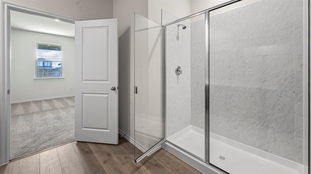 Walk-in shower with clear glass enclosure and tile-look wall panels