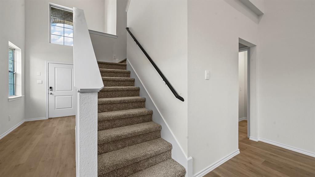 Two-story entryway with wood-finish flooring, a carpeted staircase, and high ceilings