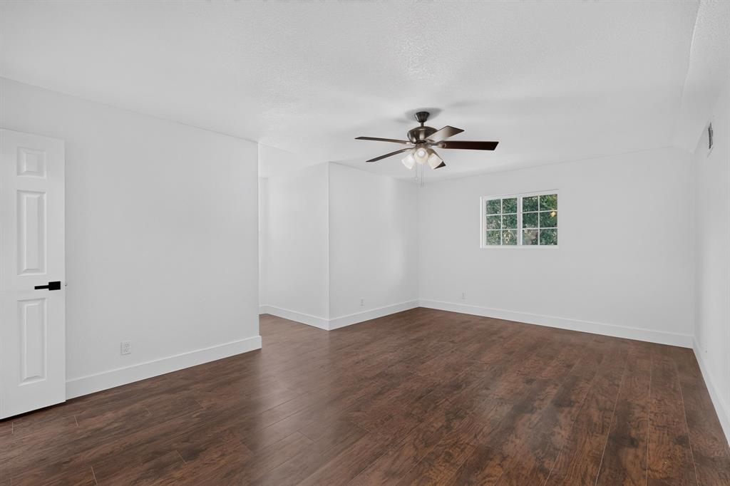Interior space featuring wood-finish flooring, a multi-pane window, and a ceiling fan with integrated lighting