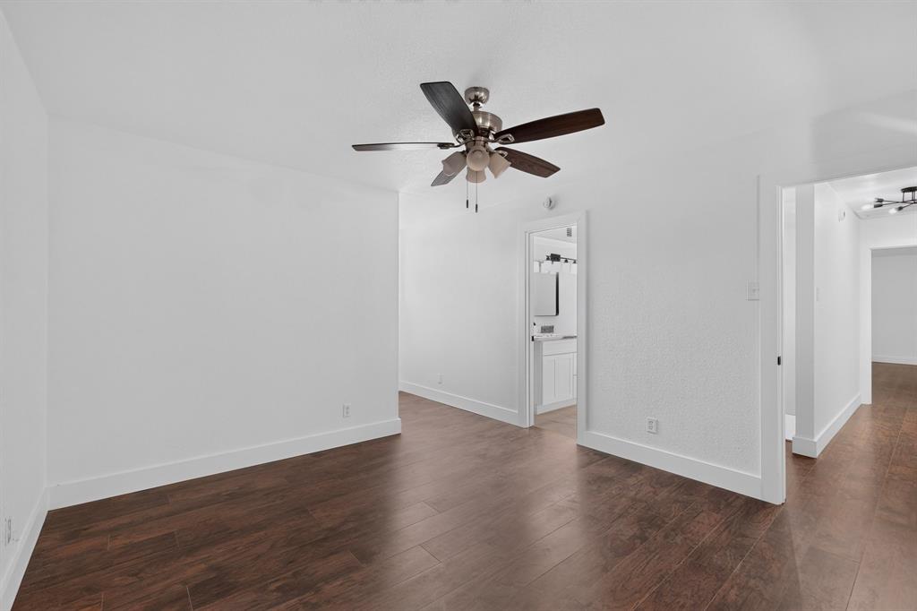 Interior space featuring wood-finish flooring, white walls, and a ceiling-mounted light fixture with a multi-blade fan