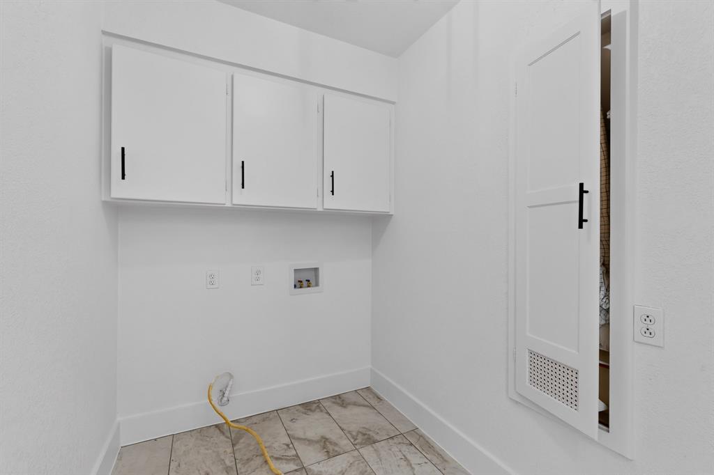 Utility room featuring white cabinetry, matte black hardware, tiled flooring, and a built-in louvered access door