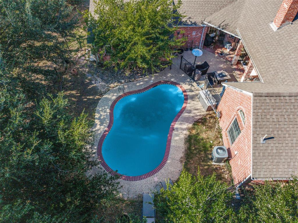 Free-form gunite pool with brick coping and expansive aggregate patio.
