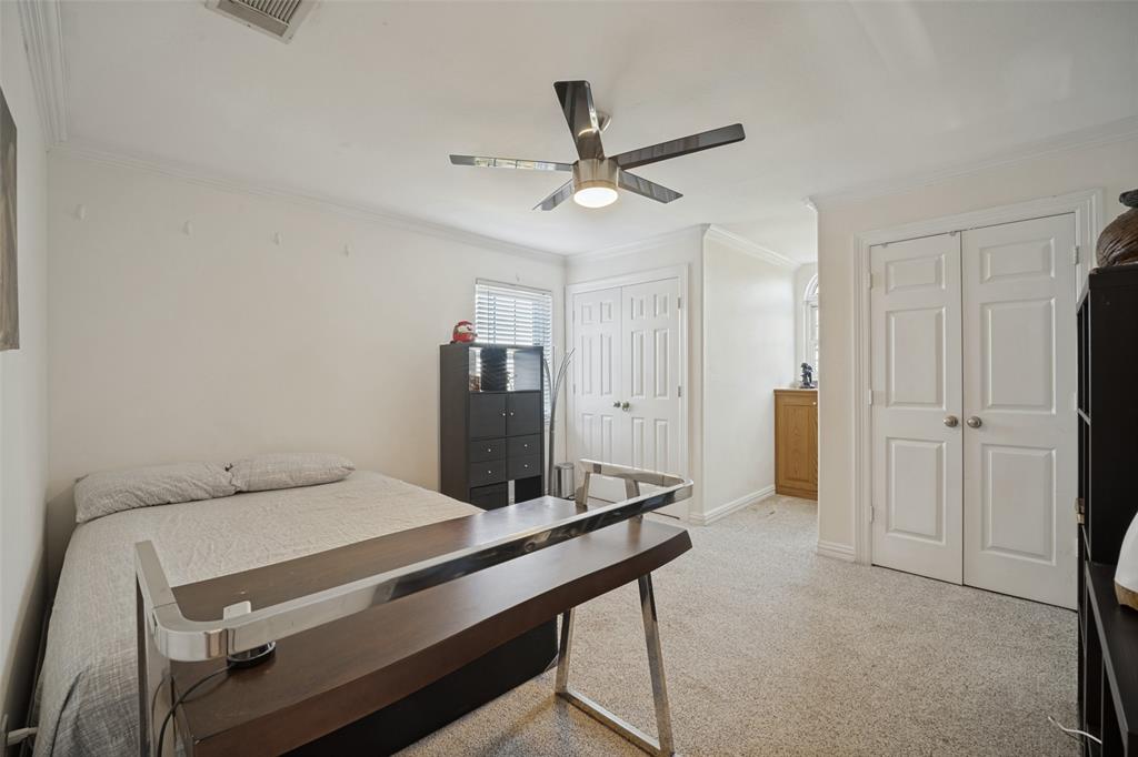 Neutral-toned room featuring a multi-blade ceiling fan, crown molding, dual-panel interior doors, and built-in cabinetry