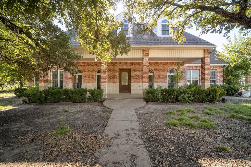 Multi-story brick and stone facade featuring arched window frames, triple dormer windows, and a covered entryway