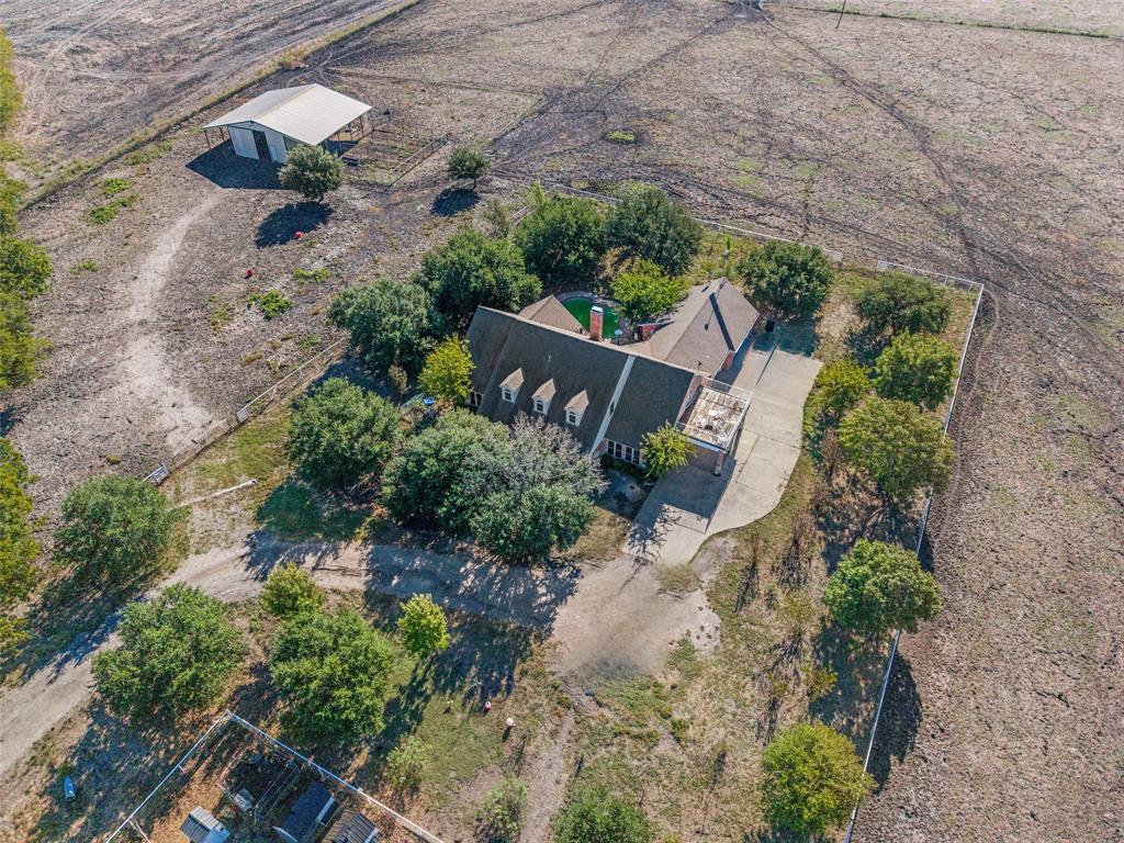 Expansive acreage featuring a multi-story residence, a detached metal barn, mature trees, and a concrete driveway