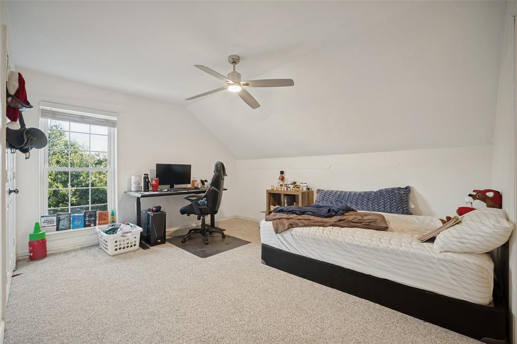 Bedroom featuring slanted ceilings, carpeting, a multi-lite window, and a ceiling fan with integrated lighting and ensuite bathroom.