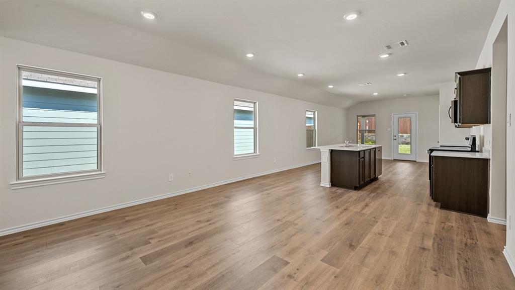 Open-concept living area featuring wood-finish flooring, recessed lighting, and ample natural light from multiple windows