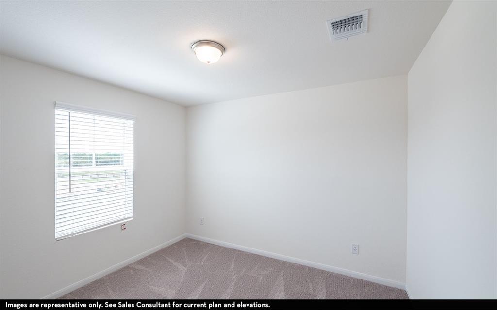 Neutral-toned interior space featuring light-colored wall paint, carpeted flooring, a single-window configuration with horizontal blinds, and a flush-mount ceiling light fixture