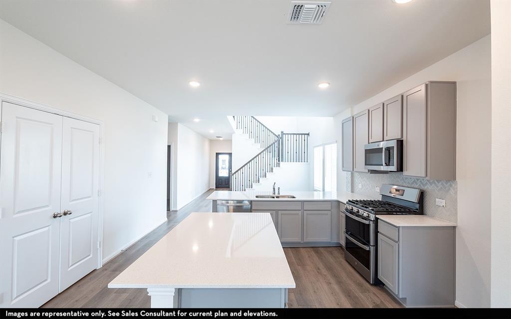 Kitchen featuring a central island with a quartz countertop, gray shaker-style cabinetry, a stainless steel gas range, and wood-finish flooring