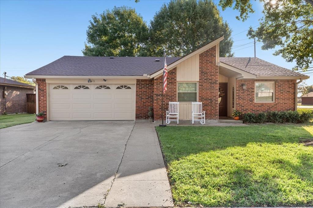 Mid-century modern architectural details featuring red brick siding, a distinctive asymmetrical roofline, attached multi-car garage, and a covered front entryway