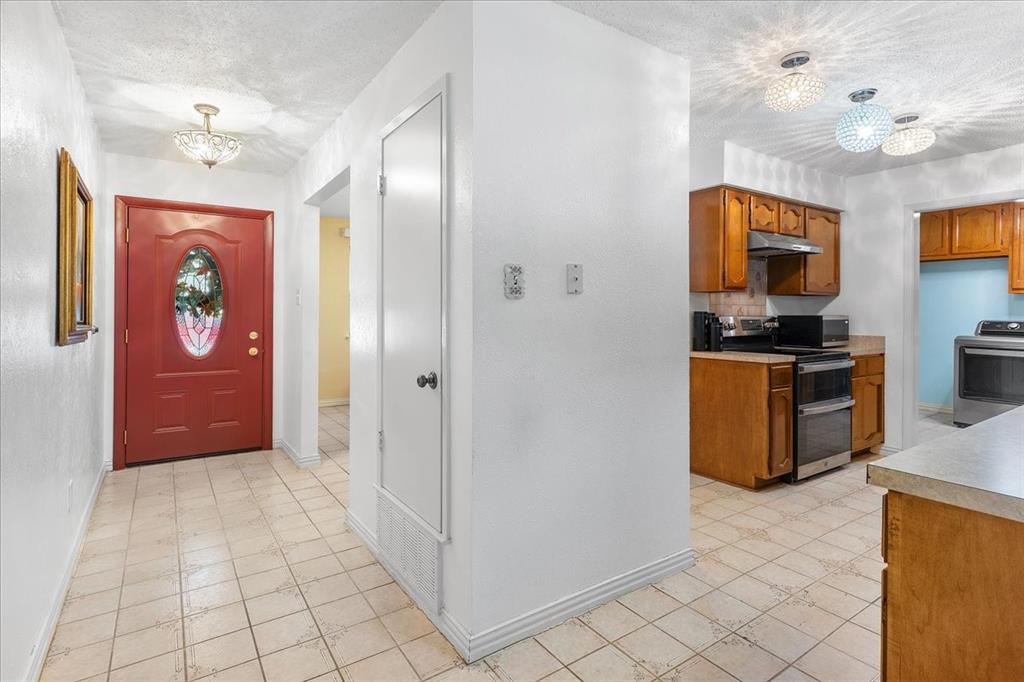 Entryway featuring a red paneled door with an oval glass insert, tile flooring, built-in storage closet, and decorative globe-style light fixtures