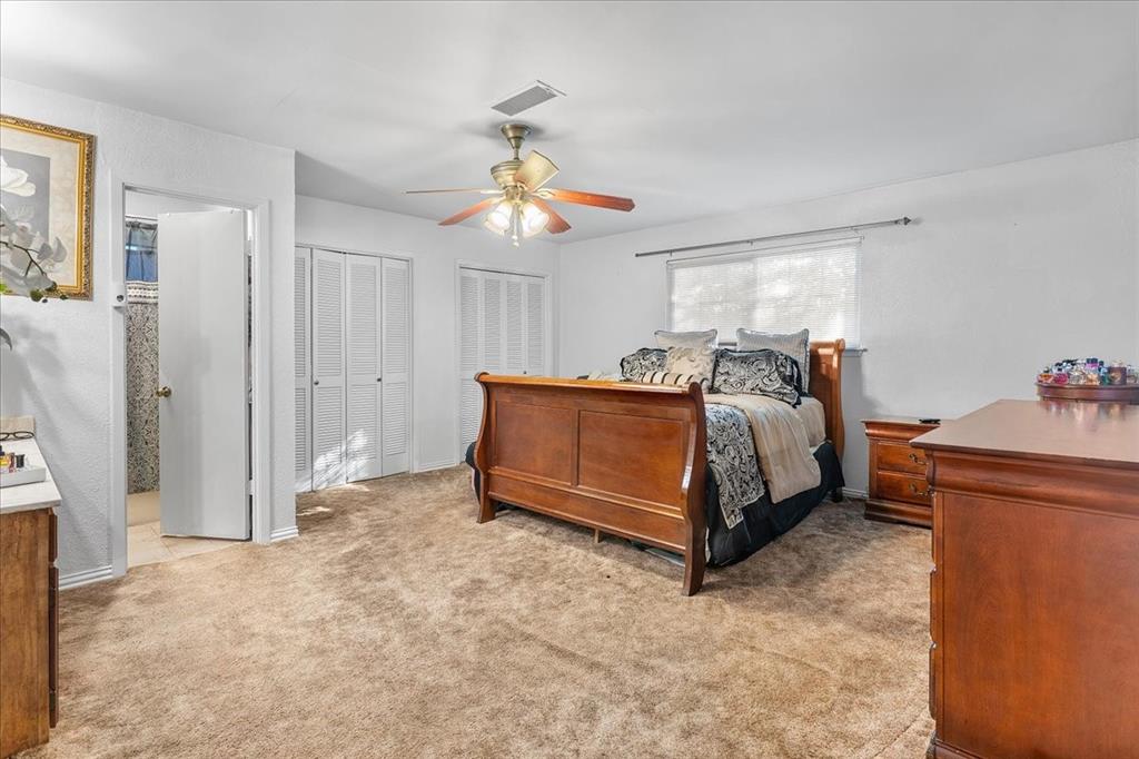 Room featuring carpeted flooring, a ceiling fan with integrated lighting, dual louvered closet doors, and a horizontal window