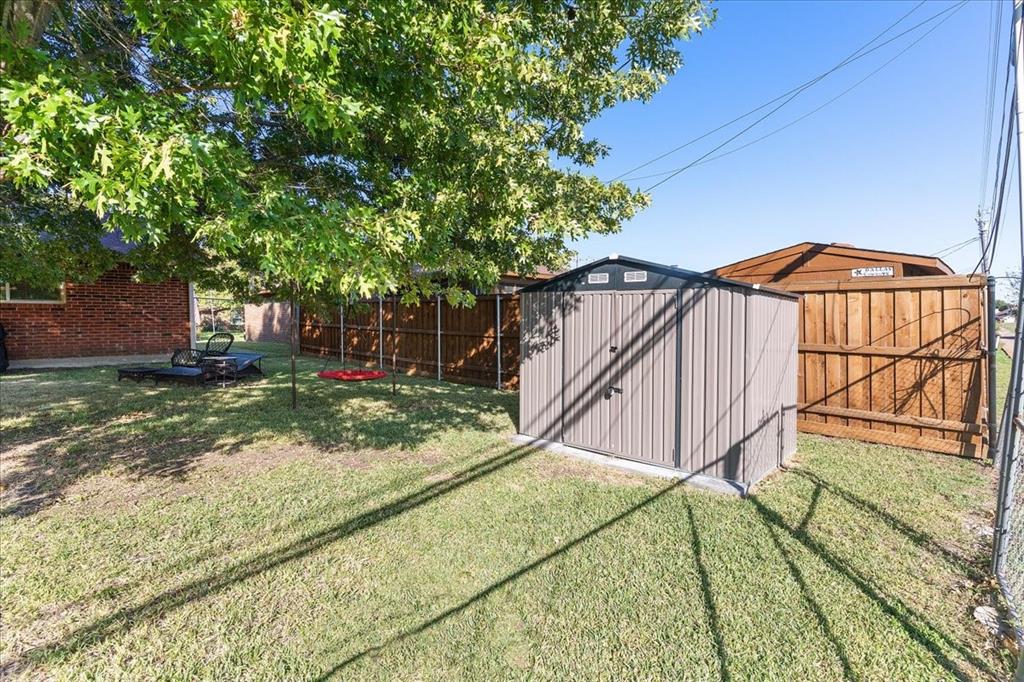 Backyard space featuring a metallic storage shed, privacy fencing, and mature tree canopy