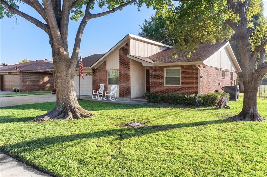 Single-story exterior featuring a brick and panel facade, attached garage, composition shingle roof, and mature trees Single-story exterior featuring a brick and panel facade, attached garage, composition shingle roof, and mature trees