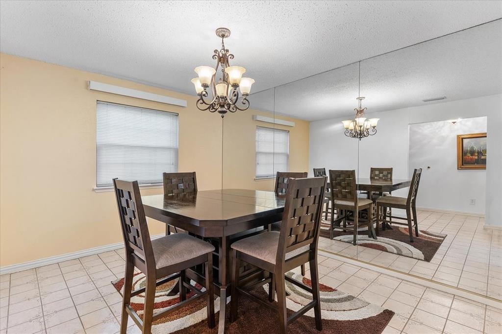 Tile flooring, decorative metal chandelier, and wall-to-wall mirrored paneling