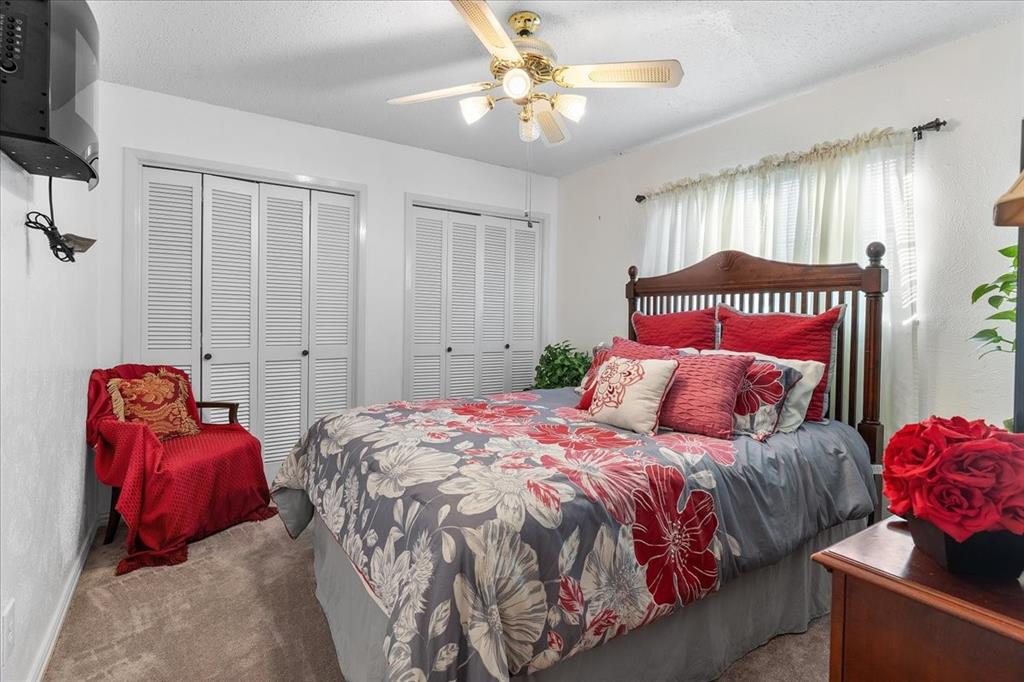 Interior space featuring neutral-toned carpeting, dual louvered-style closet doors, and a multi-light ceiling fan Interior space featuring neutral-toned carpeting, dual louvered-style closet doors, and a multi-light ceiling fan