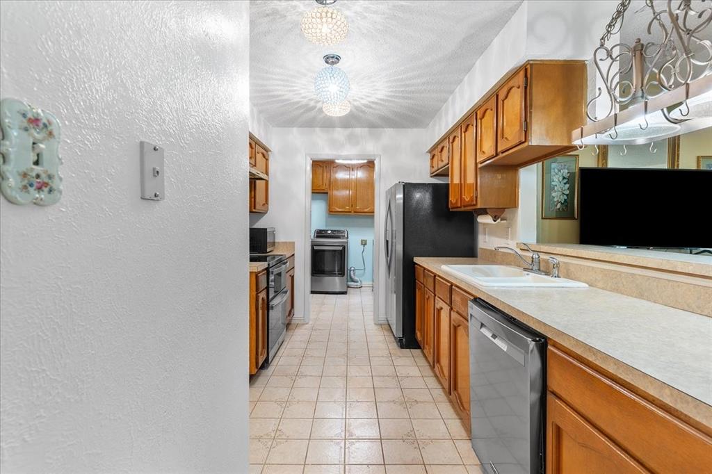 Kitchen featuring wood cabinetry, tile flooring, stone-surfaced countertops with an integrated double sink, and decorative globe lighting fixtures