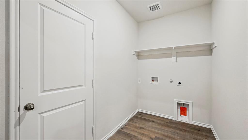 Dedicated laundry area featuring wood-finish flooring, white walls, and a built-in storage shelf