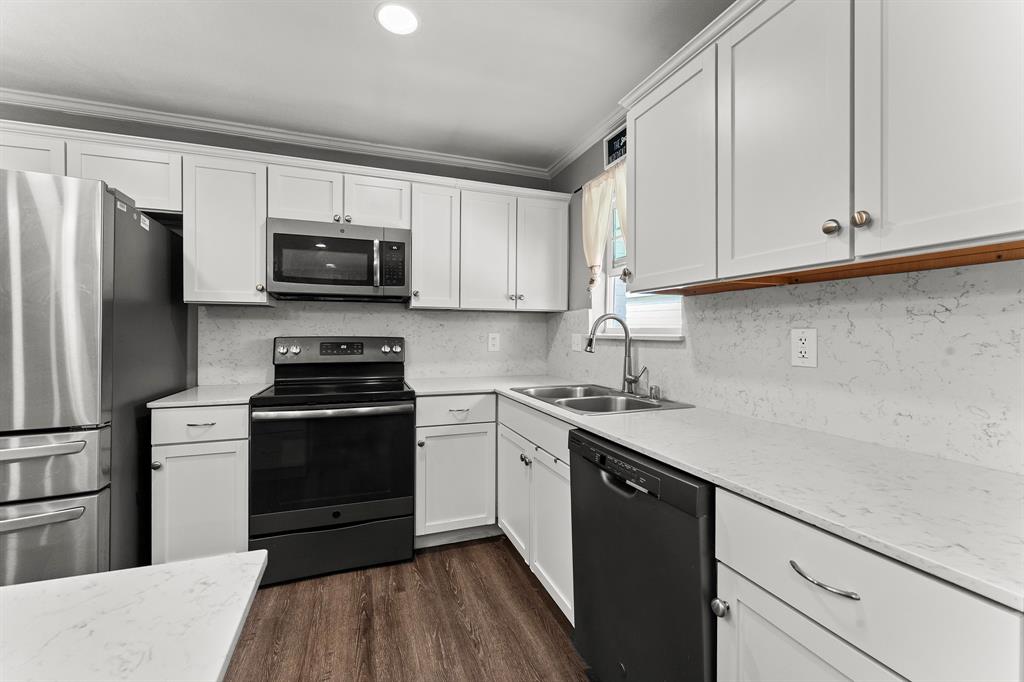 Kitchen featuring white cabinetry, quartz countertops with a subtle vein pattern, stainless steel appliances, a double-basin undermount sink, and wood-finish flooring
