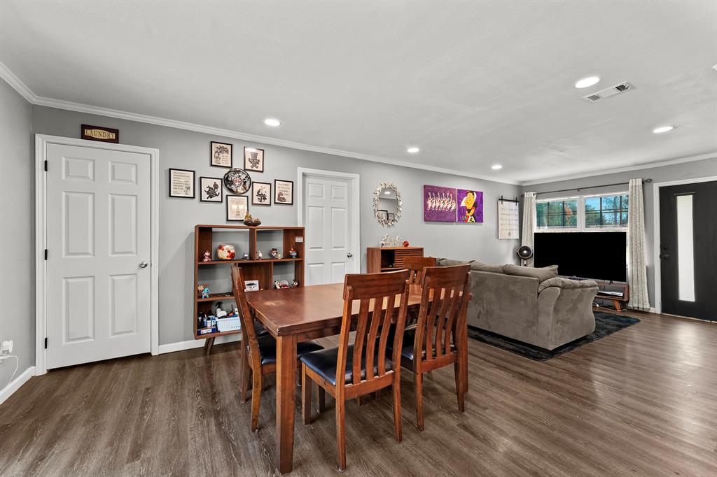 Open-concept interior featuring wood-finish flooring, recessed lighting, neutral wall paint, and an exterior door with a decorative glass panel