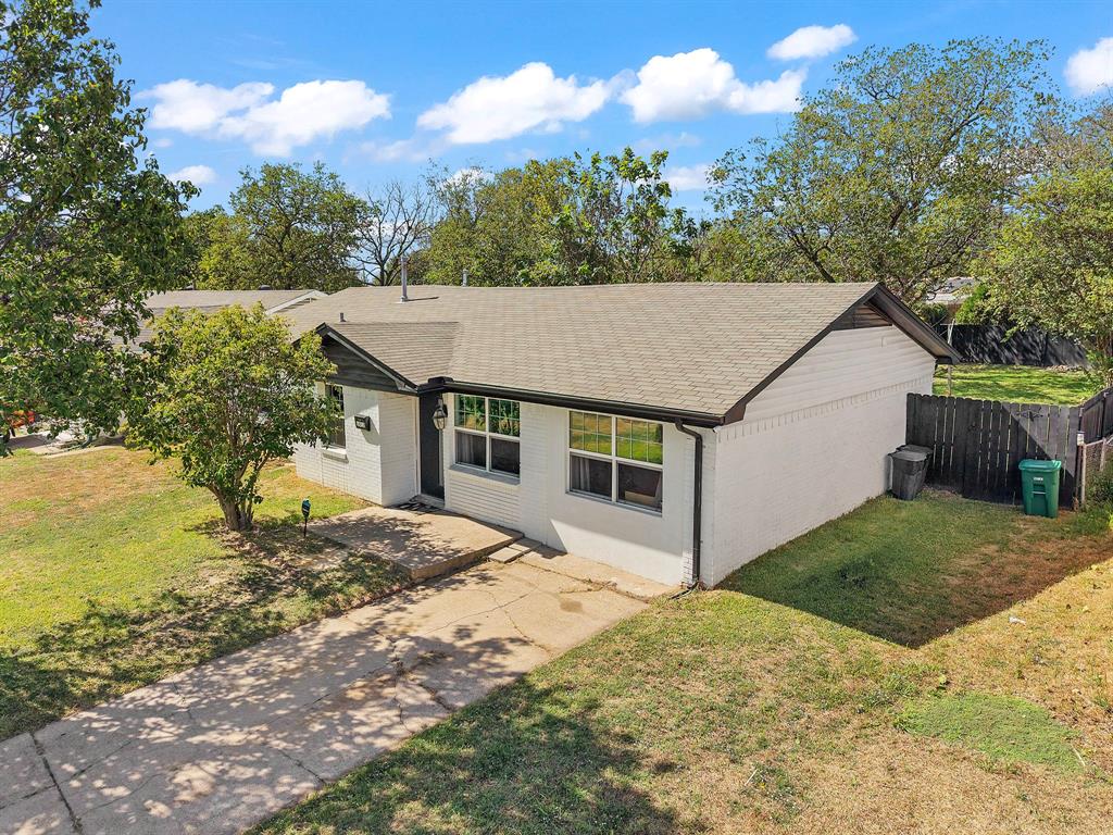 Single-story residence featuring a painted masonry exterior, gable roofline, concrete driveway, and a fenced backyard