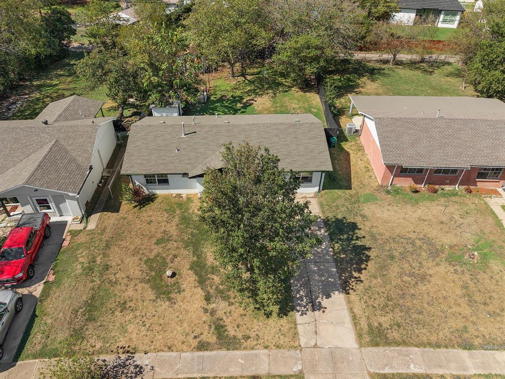 Residential property featuring a concrete driveway, low-pitch shingle roof, white exterior siding, and mature trees