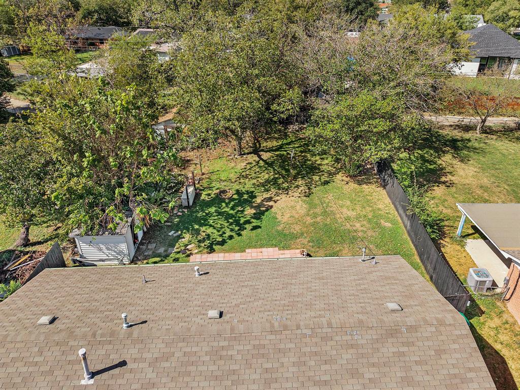 Expansive backyard featuring mature shade trees, a grass lawn, paved patio, and privacy fencing
