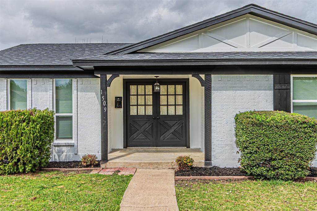 Painted brick exterior featuring decorative gable trim, double-door entrance with X-panel detailing, multi-pane glass inserts, and a covered front porch