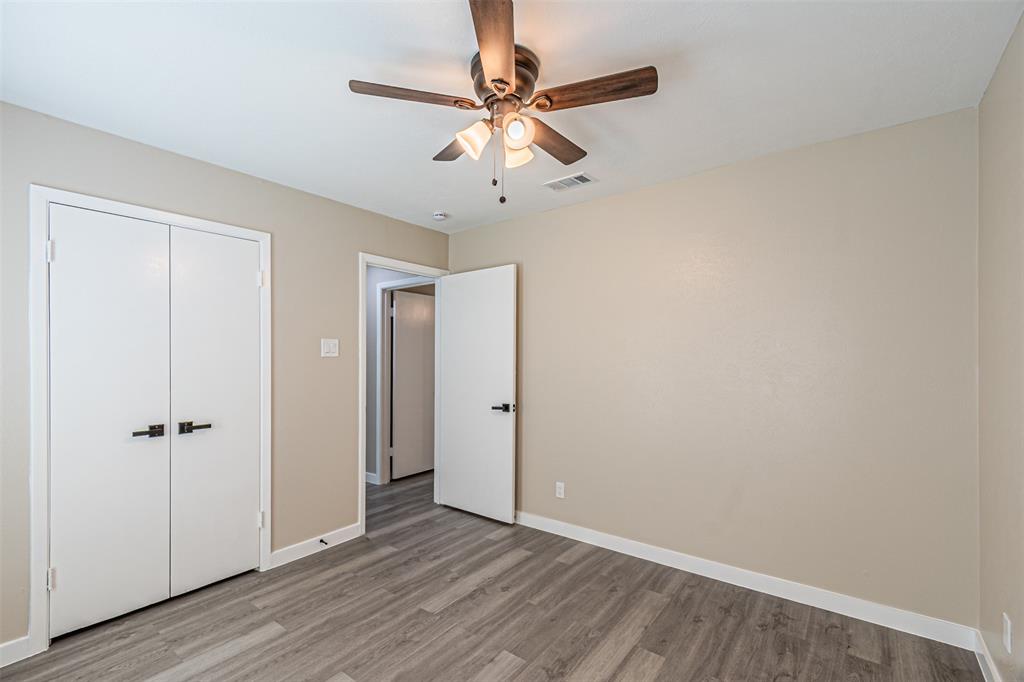 Wood-finish flooring, ceiling fan with integrated lighting, and white interior doors featuring matte black hardware