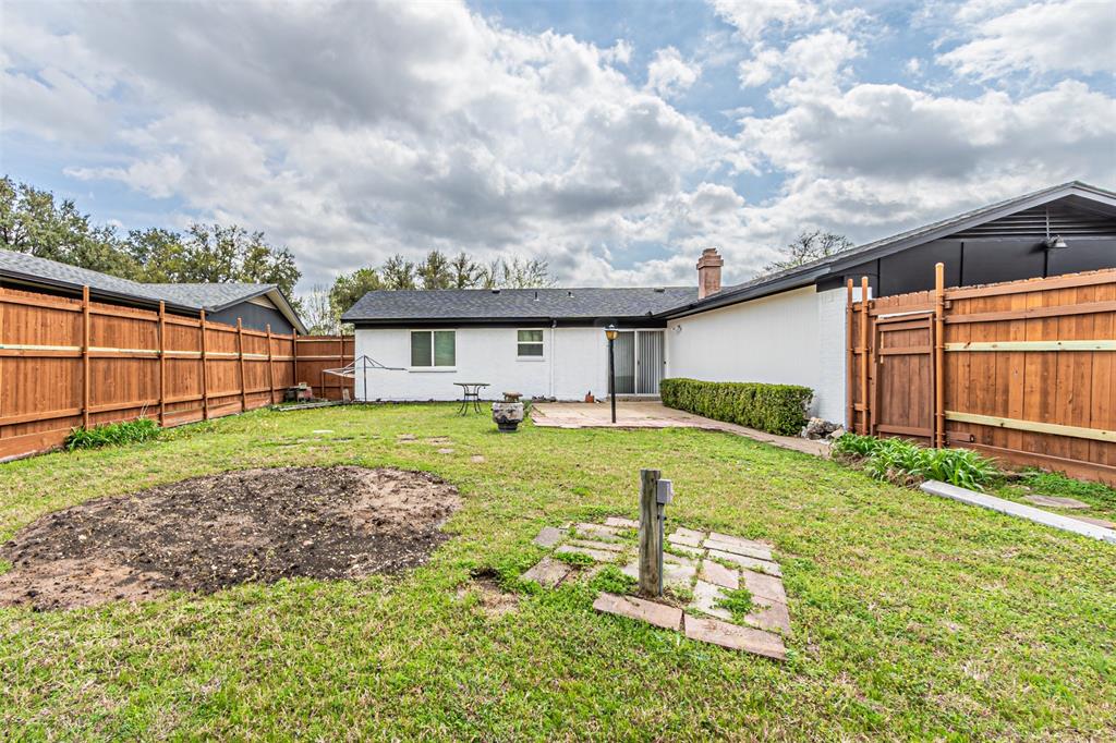 Backyard featuring a privacy wood fence, stone patio, and exterior brick finish