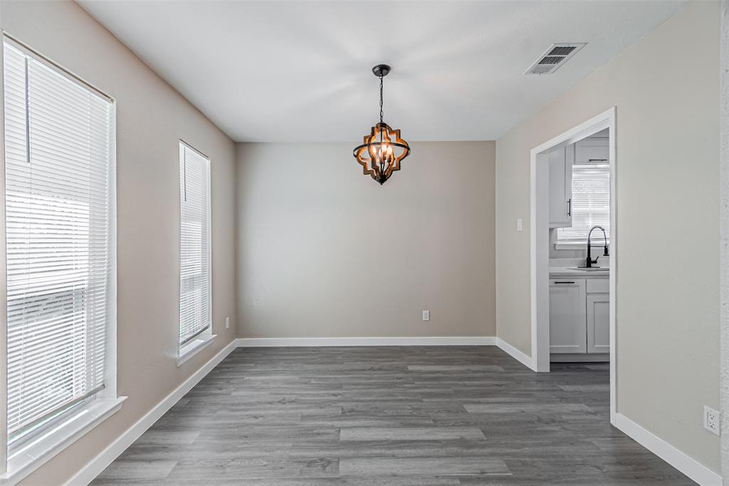 Neutral wall tones, wood-finish flooring, two large windows with blinds, and a multi-bulb lantern pendant fixture