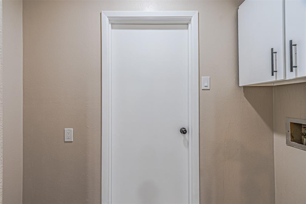 Interior door featuring a crisp white finish with a circular knob, paired with white upper cabinetry and brushed metal hardware