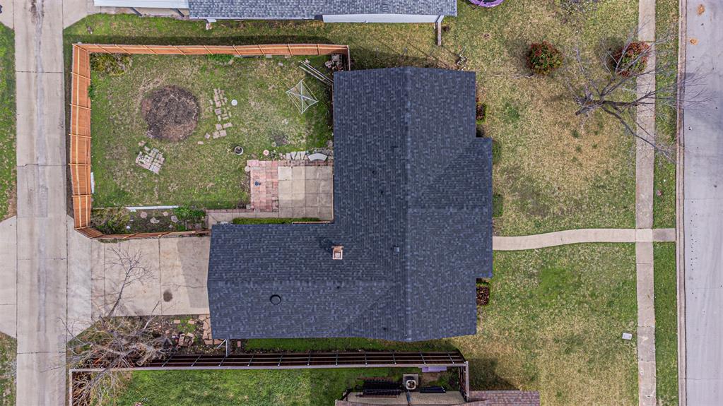 Aerial view featuring a fenced-in rear yard, concrete patio, asphalt shingle roof, and paved driveway