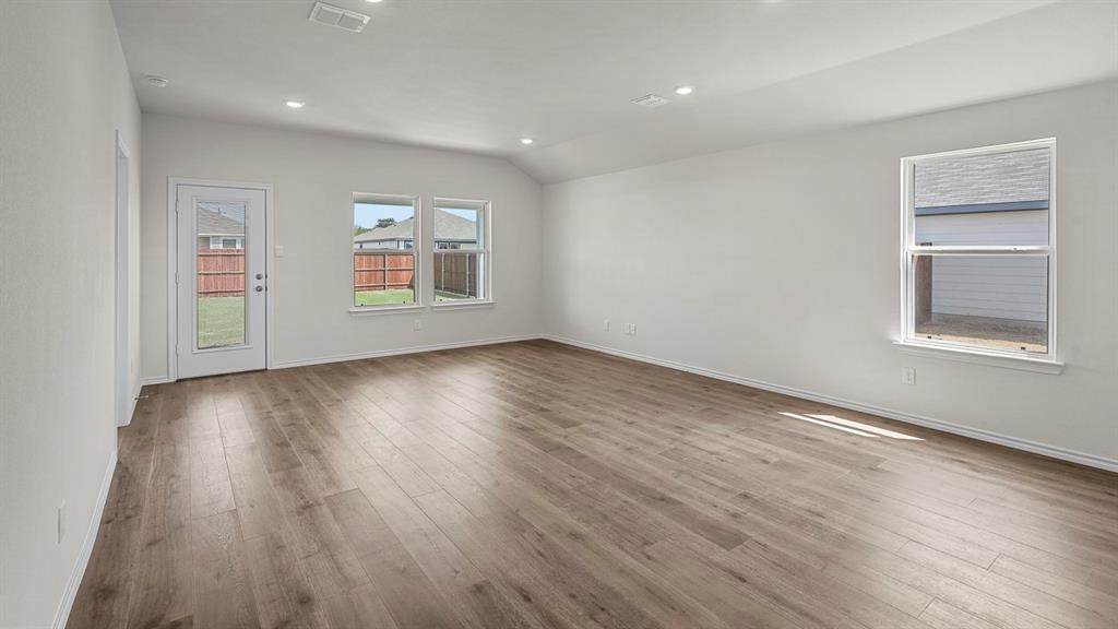 Interior space featuring wood-finish flooring, vaulted ceilings, recessed lighting, and multiple windows