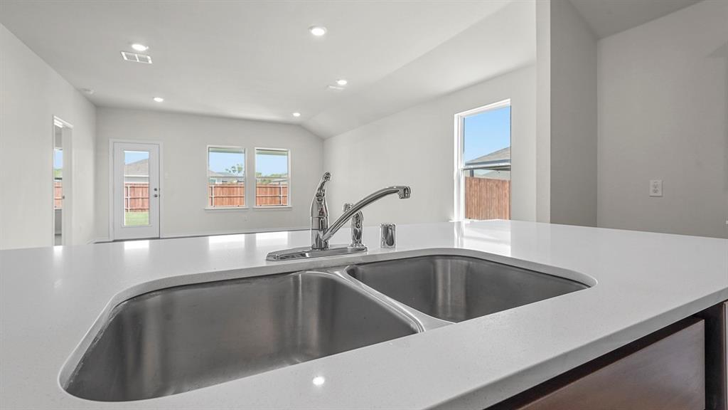 Quartz countertops, stainless steel double-basin undermount sink, high-arc faucet, and recessed ceiling lighting