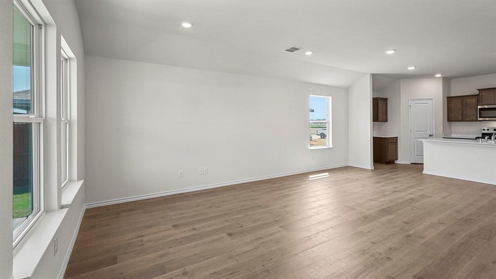 Open-concept interior featuring wood-finish flooring, recessed lighting, vaulted ceilings, and large windows