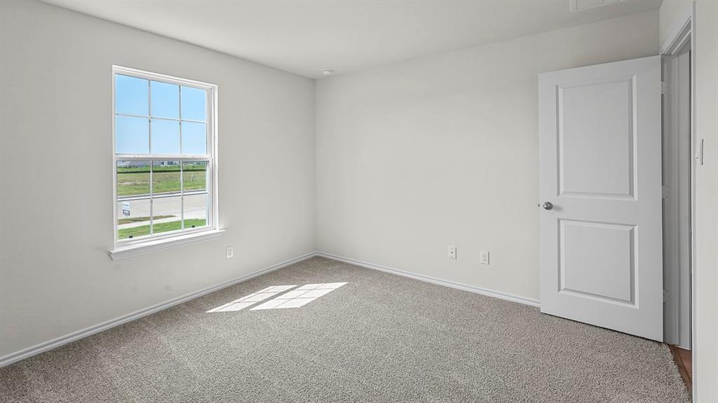 Neutral-toned room featuring wall-to-wall carpeting, a single-hung window with a grid pattern, and a two-panel interior door Neutral-toned room featuring wall-to-wall carpeting, a single-hung window with a grid pattern, and a two-panel interior door