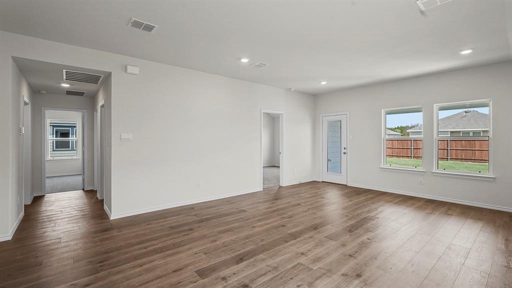 Open-concept interior featuring wood-finish flooring, recessed lighting, and multiple windows providing natural light, inclusive of a glass-paneled exterior door