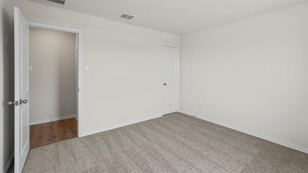 Neutral-toned wall paint, wall-to-wall carpeting, two-panel interior doors with brushed nickel hardware, and wood-finish flooring visible through the doorway Neutral-toned wall paint, wall-to-wall carpeting, two-panel interior doors with brushed nickel hardware, and wood-finish flooring visible through the doorway