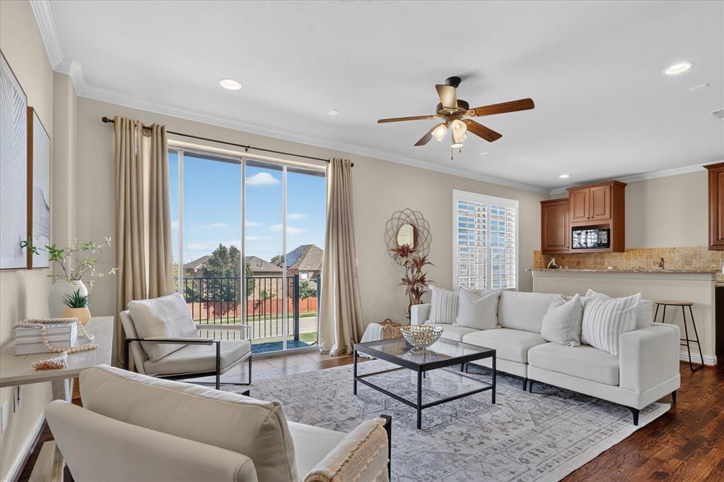 Flex space featuring handscraped hardwood flooring, full bath, two large walk in closets, laundry room, and a large wet-bar with cabinets, mini sink and mini-fridge. Sliding glass door leads to balcony with winding staircase down to covered patio.