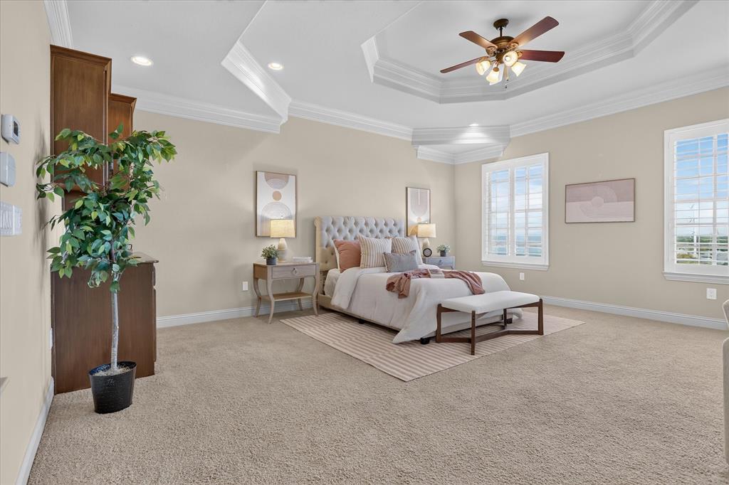 Tray ceiling with recessed lighting, integrated wooden cabinetry, wall-to-wall carpeting, and plantation shutters