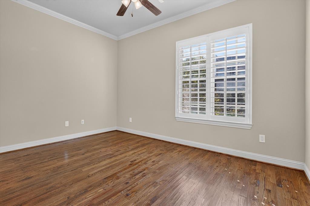 Wood-finish flooring, crown molding, white plantation shutters, and a ceiling fan with integrated lighting