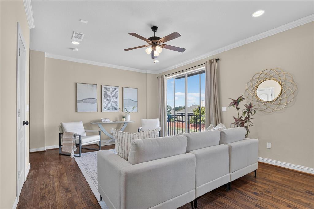 Flex space featuring handscraped hardwood flooring, full bath, two large walk in closets, laundry room, and a large wet-bar with cabinets, mini sink and mini-fridge. Sliding glass door leads to balcony with winding staircase down to covered patio.