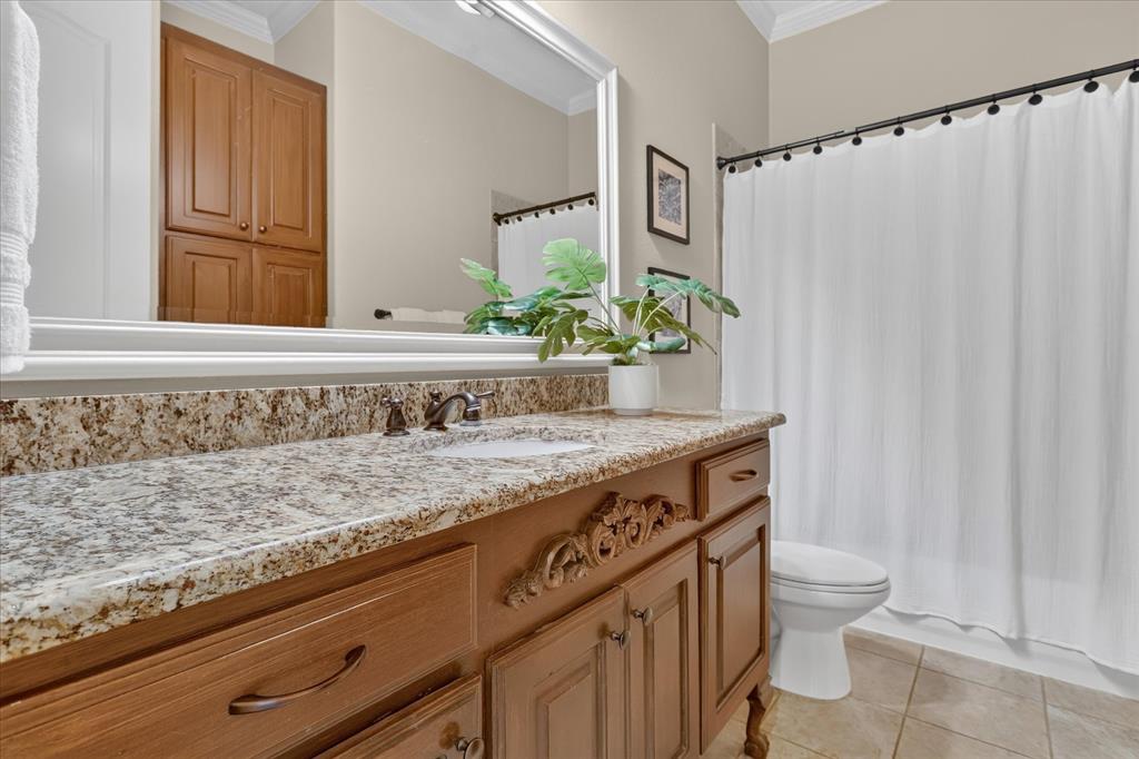Bathroom featuring a stone-topped vanity with decorative wood cabinetry, large wall-mounted mirror, ceramic tile flooring, and a shower-tub combination