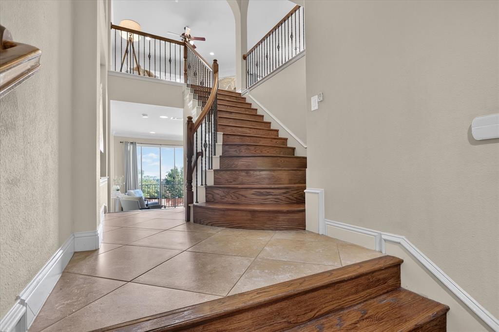 Grand entryway featuring stone tile flooring, a curved staircase with stained wood treads, and metal balusters